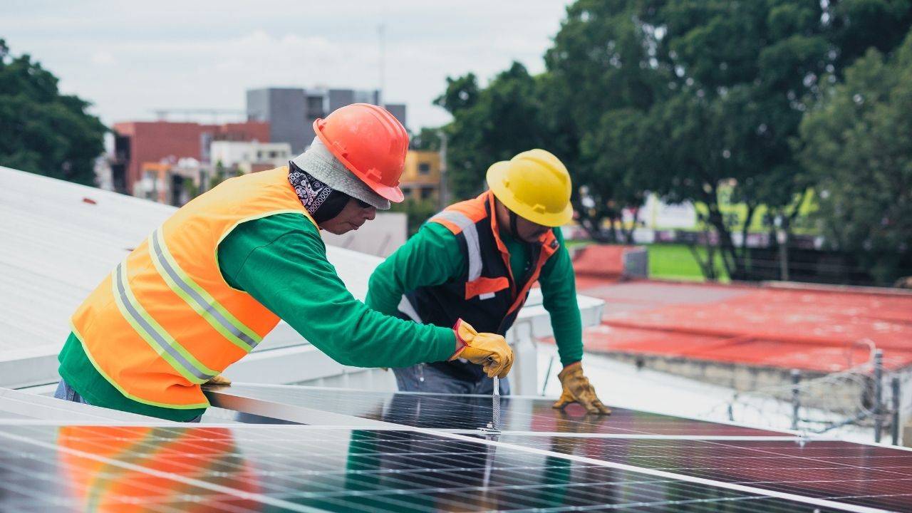 Two electricians work on a solar panel.