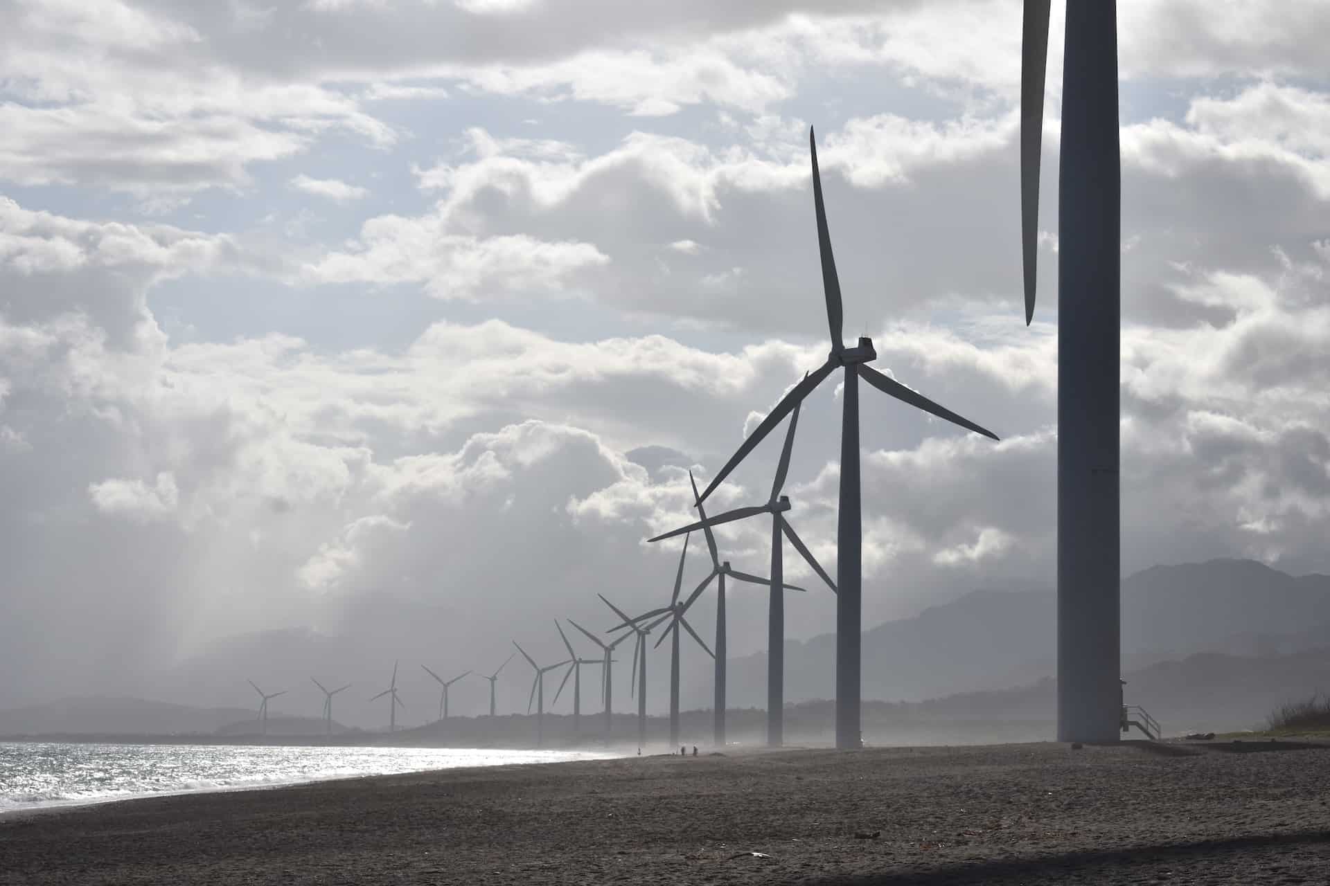 Wind turbines lined up along a coastline in the Philippines.